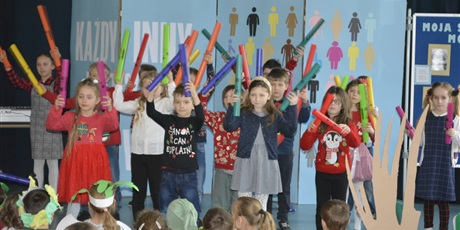 Powiększ grafikę: Śpiewające i kolorowymi patykami z gąbki dzieci z klasy II stojące na scenie