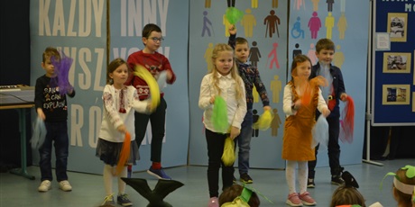 Powiększ grafikę: Siedmioro dzieci z klasy I tańczą na scenie tańczą i machają mocno z kolorowymi pomponami.