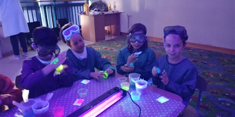 Powiększ grafikę: Dzieci siedzą przy stoliku w okularach ochronnych na zajęciach "Małego chemika"