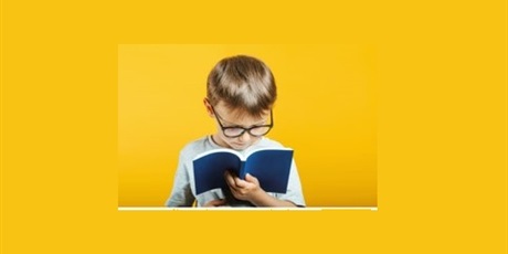 Powiększ grafikę: Chłopiec w okularach, w białej koszulce czyta książkę w niebieskiej okładce, żółte tło zdjęcia.