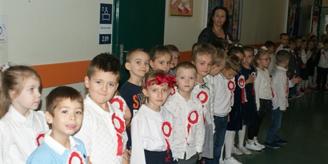 Powiększ grafikę: Uczniowie klas młodszych stoją na korytarzu szkolnym prze uroczystym odśpiewaniem hymnu państwowego 