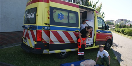 Powiększ grafikę: Samochód FALC przy którym pani ratowniczka pokazuje dzieciom na fantomie jak udzielić pierwszej pomocy