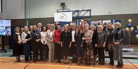 Powiększ grafikę: Dyrektorzy szkół trójmiejskich, mężczyźni i kobiety, 24 osoby, pozują uśmiechnięci do zdjęcia na sali gimnastycznej.