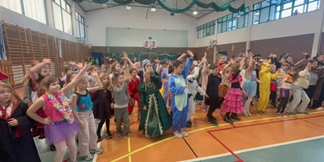 Powiększ grafikę: dziewczynki i chłopcy z klas młodszych tańczą na sali gimnastycznej w strojach karnawałowych