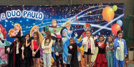 Powiększ grafikę: dzieci na sali gimnastycznej w strojach karnawałowych stoją pod plakatem