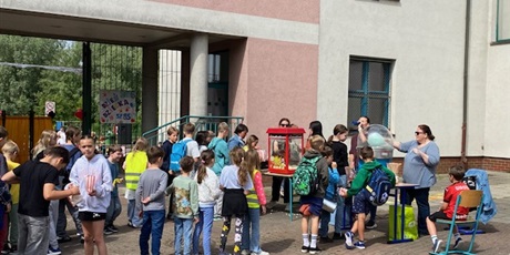 Powiększ grafikę: Dzień Dziecka, dzieci na dziedzińcu szkoły stoją w kolejce po watę cukrową i popcorn
