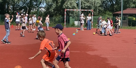 Powiększ grafikę: 2 chłopców gra w piłkę koszykową z przeszkodami na boisku szkolnym