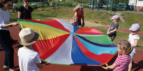 Powiększ grafikę: dzieci trzymają wielkie kolorowe materiałowe koło