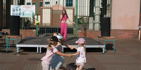 Powiększ grafikę: na scenie dziewczynka w różowym stroju spiewa a dzieci tańczą przed
