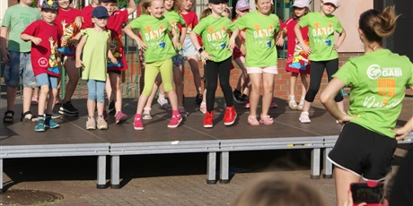 Powiększ grafikę: dzieci na scenie w kolorowych strojach, pokaz szkoły tańca