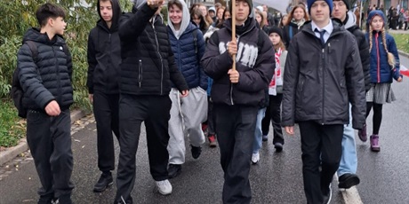 Powiększ grafikę: Uczniowie z naszej szkoły idą ulicą w paradzie. Jeden z nich trzyma logo naszej szkoły.