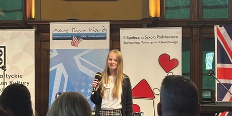 Powiększ grafikę: Dziewczynka uśmiechnięta stoi z mikrofonem  na scenie