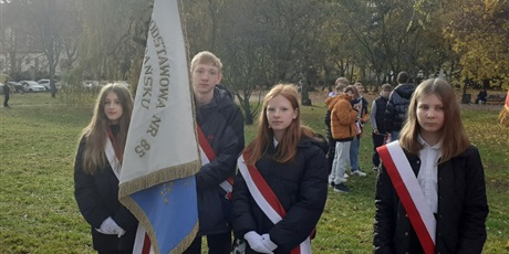 Powiększ grafikę: uczniowie klasy 7c Karol Zdziennicki, Martyna Dawczak oraz Aniela Kłoczyńska stoją ze sztandarem szkoły na trawniku