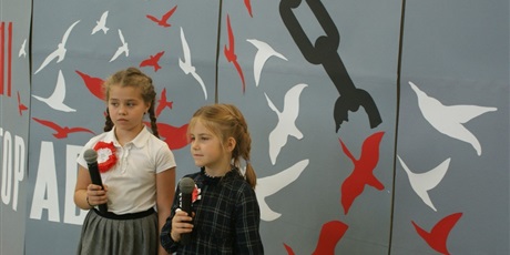 Powiększ grafikę: Dwie dziewczynki z mikrofonami przygotowują się do śpiewania na apelu z okazji 11 listopada