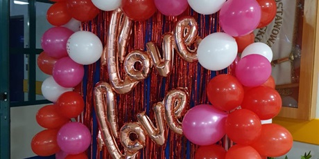 Powiększ grafikę: dekoracja na tablicy w holu 2 złote balony z napisem love a z boku tradycyjne okrągłe czerwono-różowo-białe balony