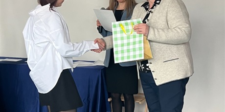 Powiększ grafikę: pani wicedyrektor wręcza nagrodę dziewczynce, obok stoi prowadząca z dyplomem i mikrofonem 