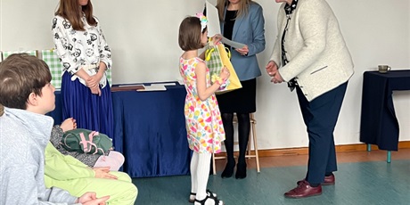 Powiększ grafikę: pani wicedyrektor wręcza dyplom i nagrodę dziewczynce, obok dwie inne nauczycielki, a z prawej strony siedzi publiczność