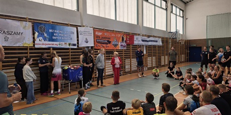 Powiększ grafikę: Uroczysta przemowa pani dyrektor i organizatorów konkursu na sali gimnastycznej. Wokół przemawiających siedzący rodzice i dzieci.