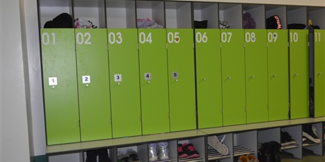 Powiększ grafikę: Zielone szafki w szatni uczniowskiej. Szafki od 1 do 5 z dodatkowym oznakowaniem językiem brajla.