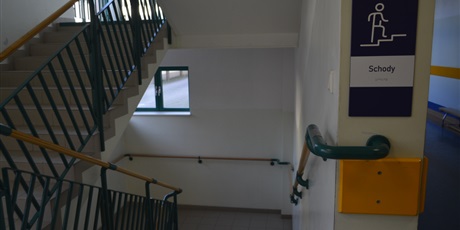 Powiększ grafikę: Korytarz szkolny. Zejście po schodach: po obu stronach poręcze oznakowane tabliczką z opisem brajlem. 